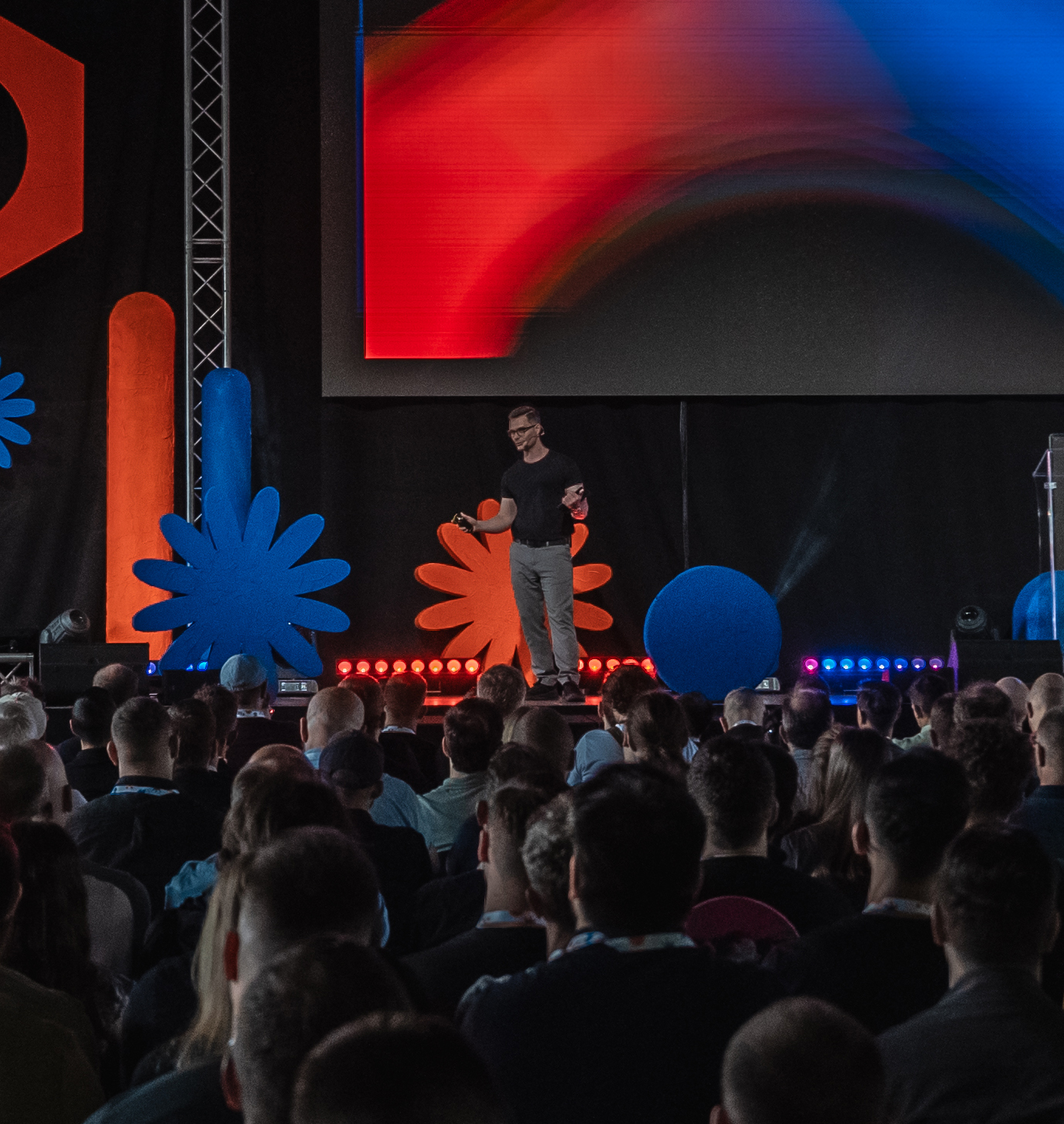 Alex MacIntosh speaking on stage in front of an audience